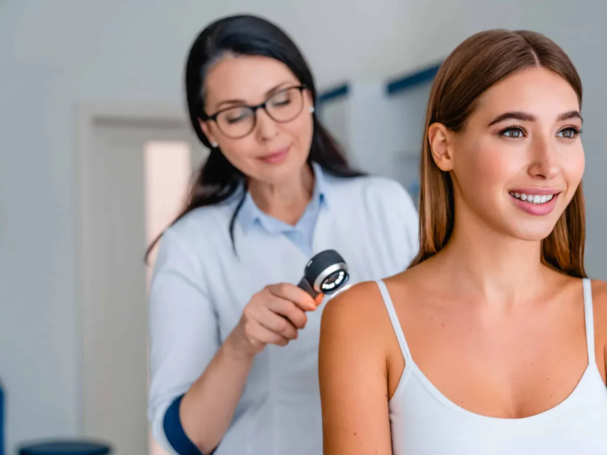 A close-up shot of a doctor examining a patient’s skin for National Healthy Skin Month