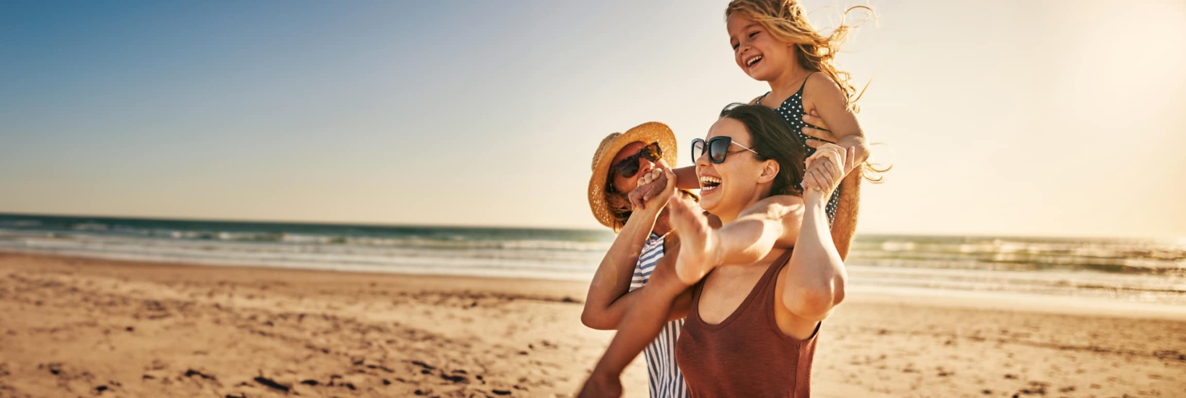 Two women and a young girl laughing together on a sunny beach