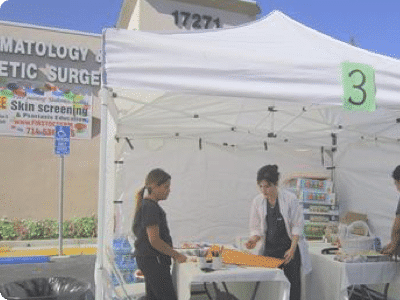 Staff at an outdoor skin screening event under a white tent outside the office