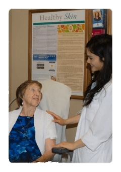 A clinician talking with a smiling older patient seated in an exam room