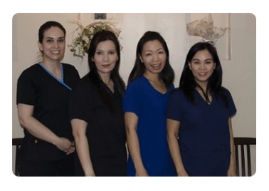 Four staff members in dark scrubs standing together in the office