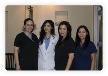 Four staff members in scrubs and a white coat standing together in the office