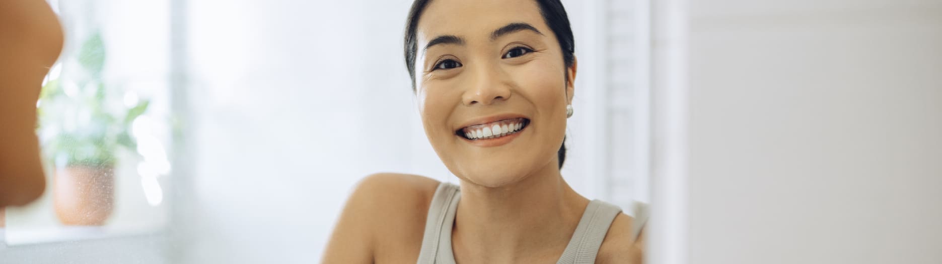 A smiling woman with dark hair pulled back looking at the camera in a bright room